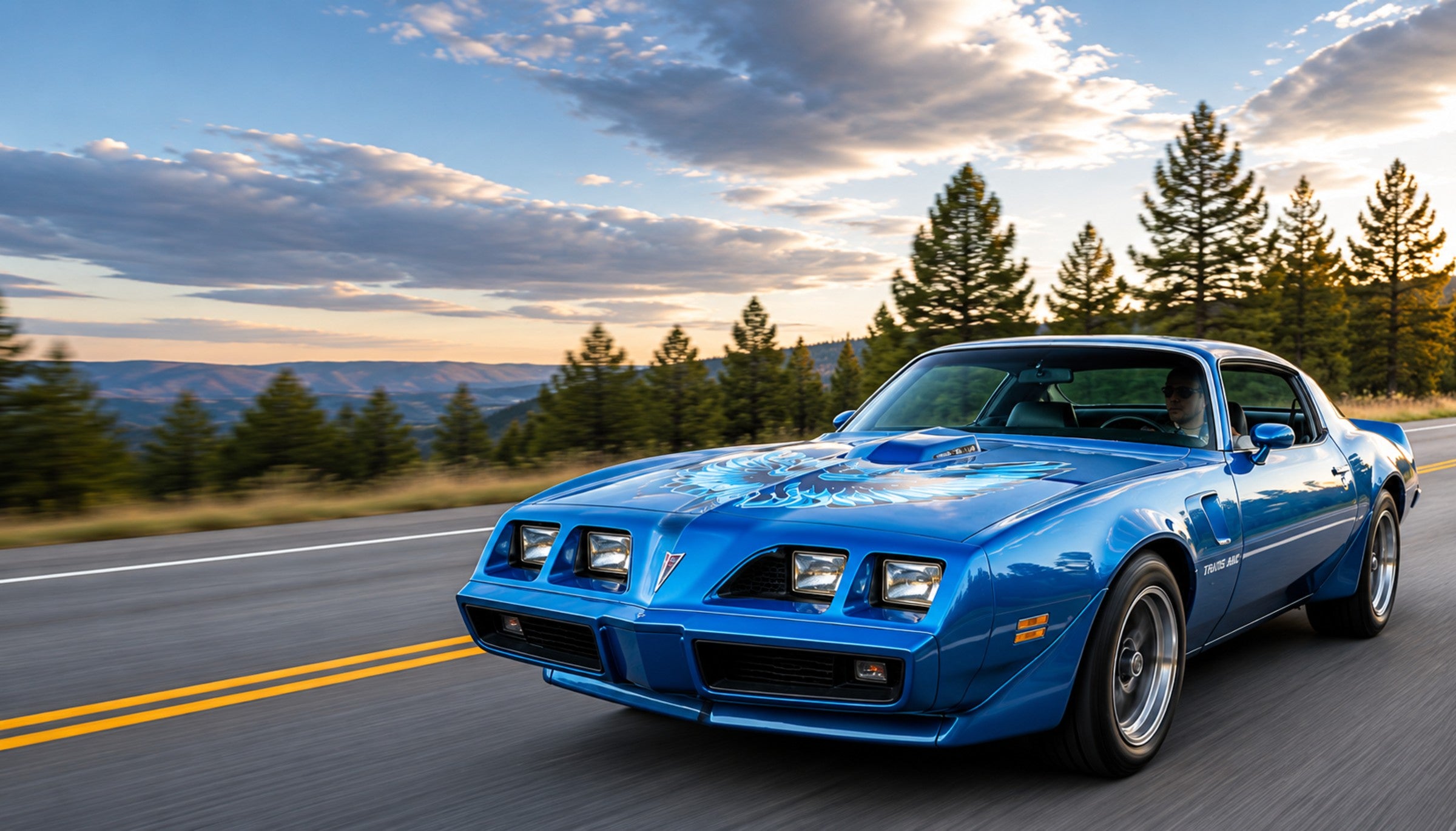 A classic Pontiac Trans Am on a tree-lined road at dusk