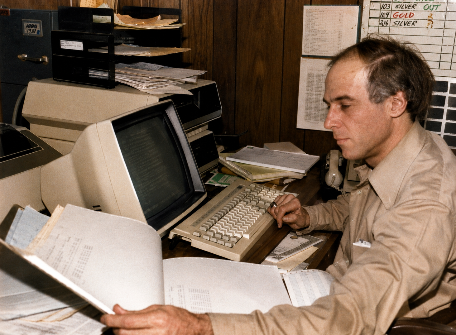 A Kanter at a computer terminal with inventory printouts in the 1980s